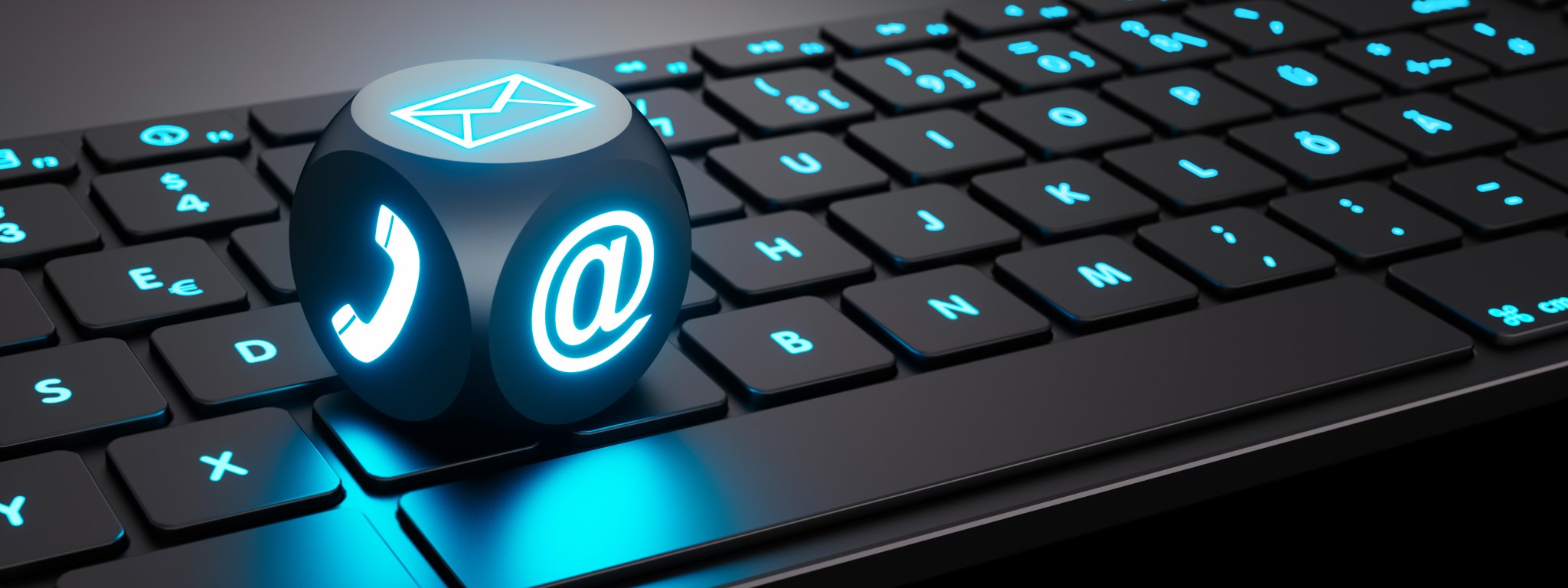 Eine blau leuchtende Tastatur mit einen Würfel auf dem ein Brief-, ein Telefon- und ein E-Mailsymbol blau leuchten.